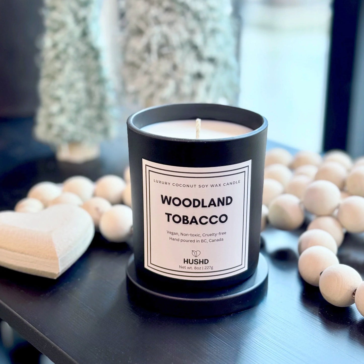 Hand-poured Woodland Tobacco candle in reusable matte black jar with warm amber and fresh woodland fragrance.